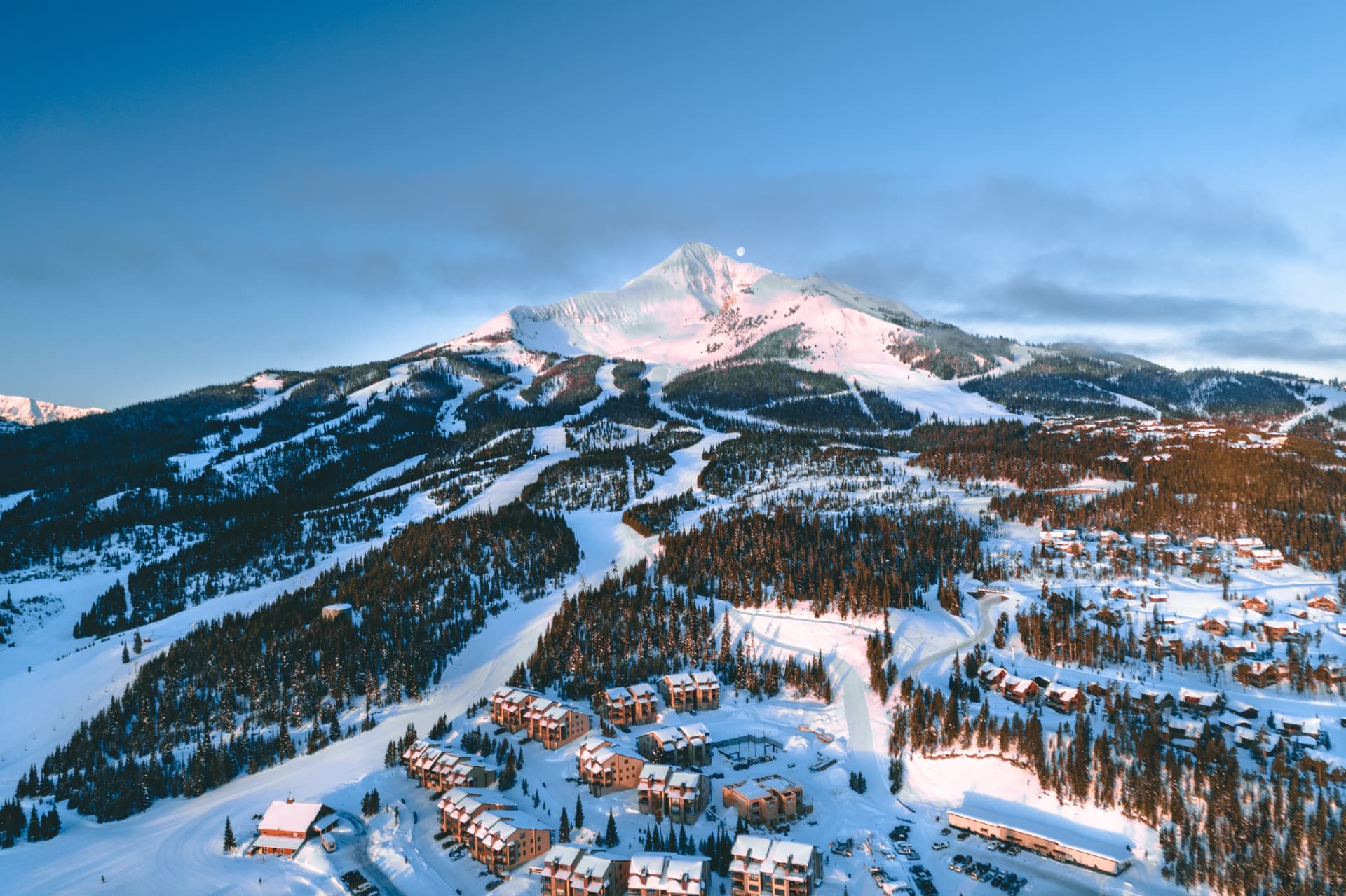 Aerial view of Lone Peak above the snow-covered slopes, forest and cabins of Big Sky, Montana