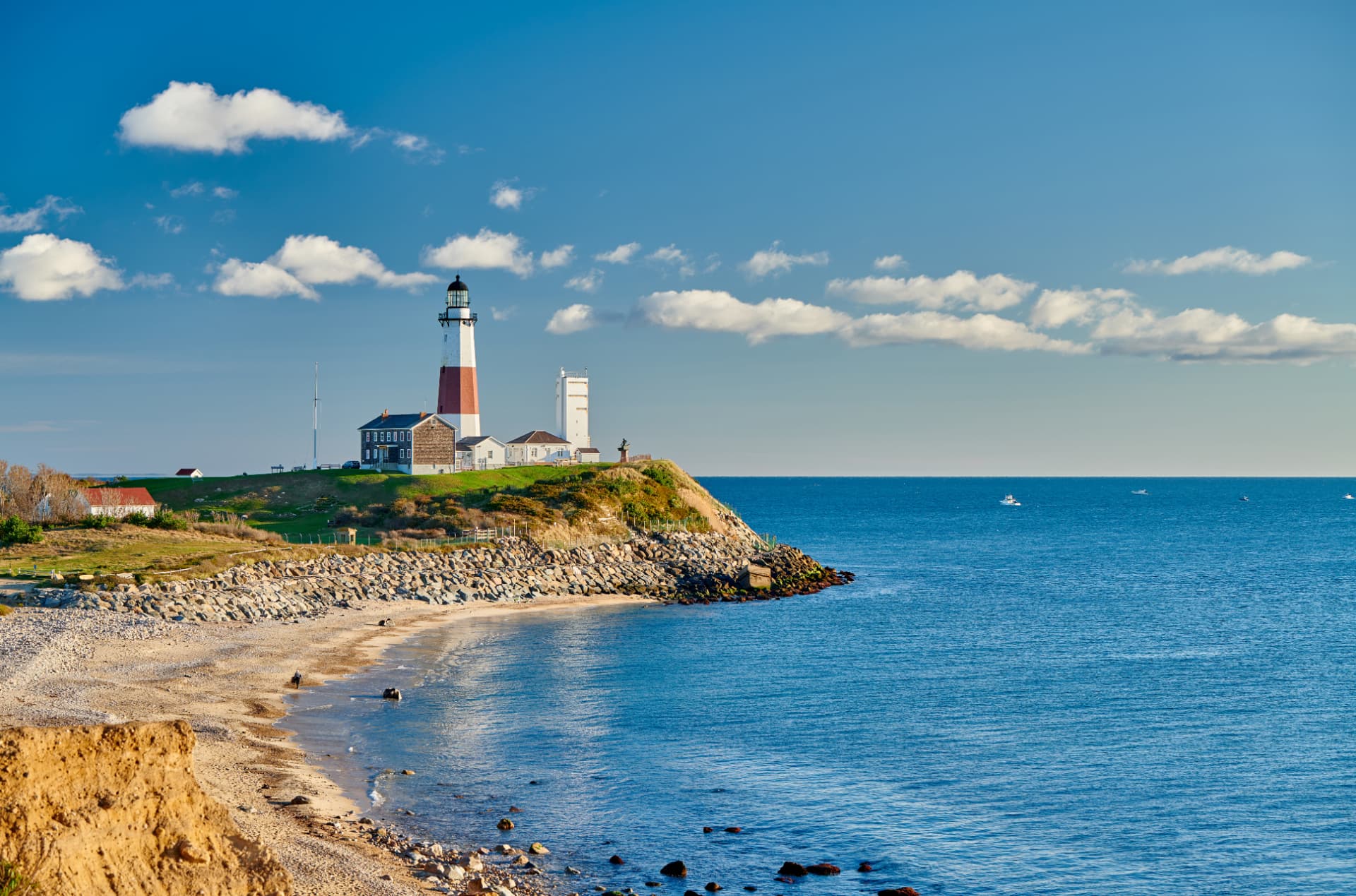 Montauk Point lighthouse on a grassy bluff above the rocky Atlantic shoreline on Long Island, New York